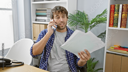 Obraz na plátně Captivating portrait of a hard-working young man, reading a business document wh