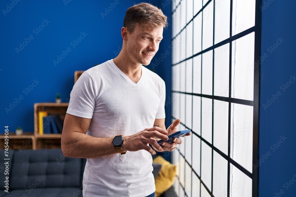Young man using smartphone standing at home Young man using smartphone standing at home