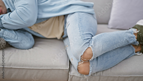 Young hispanic male, an attractive guy in the comfort of his living room, nestled indoors, resting comfortably, exhaustively sleeping on a cozy sofa at home