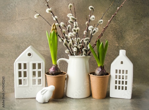 Easter composition on a brown concrete background, on the table there is a vase with willow branches and an Easter bunny.  Happy Easter holiday concept.  Space for copying text.  Foreground.