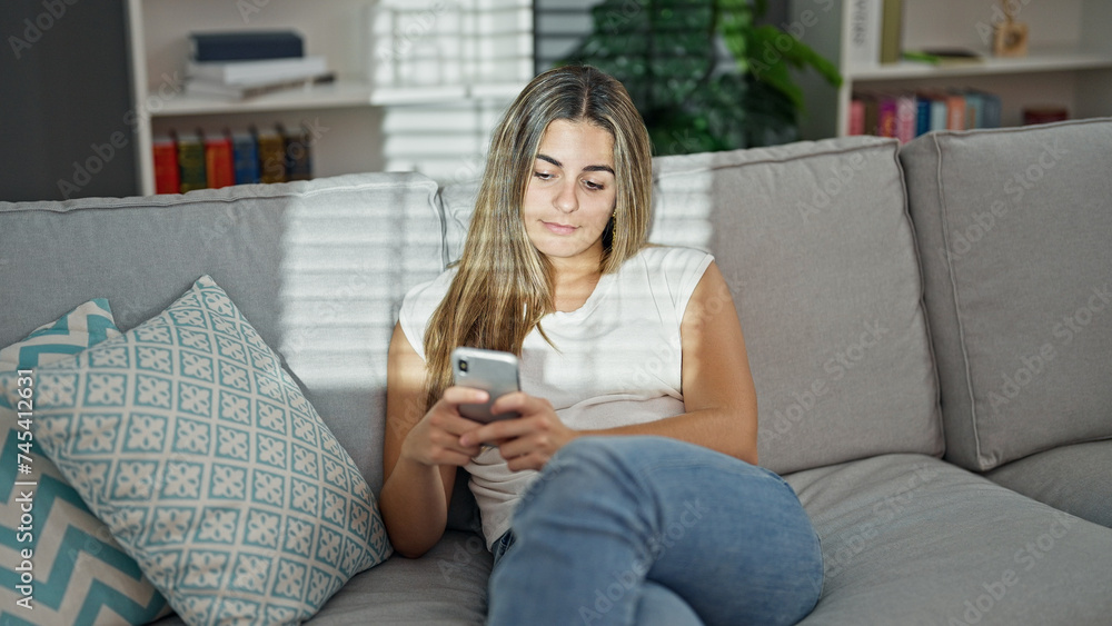 Beautiful couple using smartphone sitting on sofa at home Beautiful couple using smartphone sitting on sofa at home