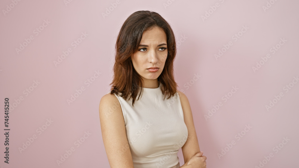 Pensive young hispanic woman with a subtle expression standing against a solid pink wall, embodying contemporary beauty. Pensive young hispanic woman with a subtle expression standing against a solid pink wall, embodying contemporary beauty.