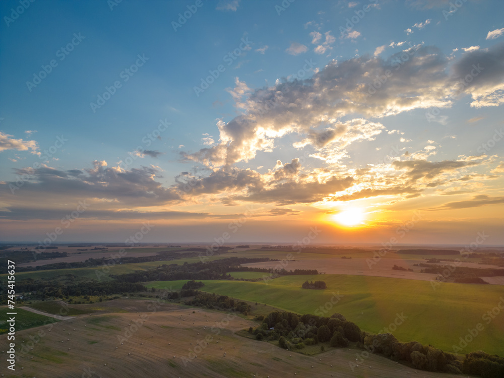Obraz premium A drone photo of a young green wheat field during sunset. Aerial view of a farmer's field. Abstract patterns and straight lines on farmland.