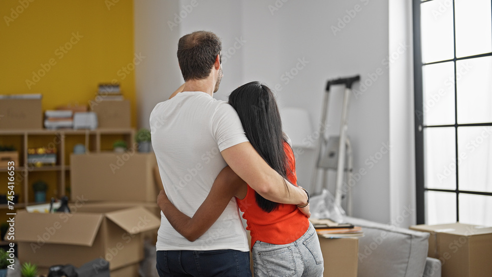 Fototapeta premium Beautiful couple standing backwards hugging each other at new home
