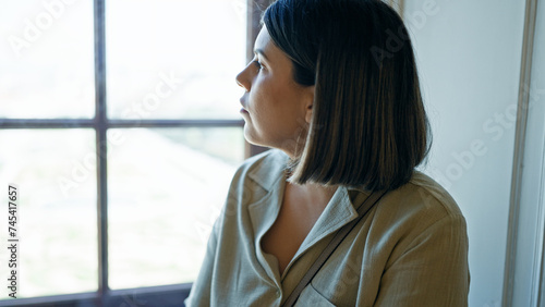 Photography Young beautiful hispanic woman sitting looking through the window at Belvedere P