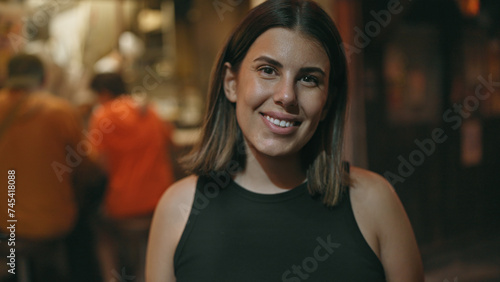 Laughing into the tokyo night, joyful, confident hispanic woman brightens shinjuku's omoide yokocho with her carefree smile. photo