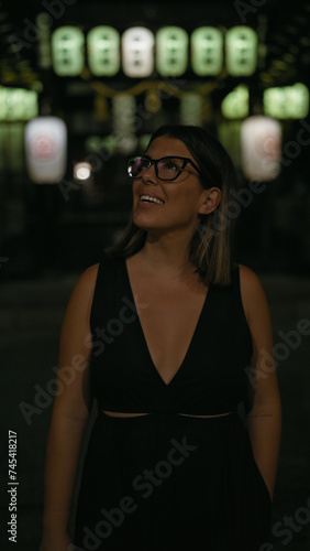 Wallpaper Mural Cheerful beautiful hispanic woman in glasses enjoying kyoto's nightlife, looking around and smiling confidently on a lighted japanese street Torontodigital.ca