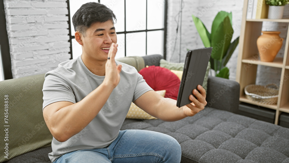 Handsome asian man enjoying a video call in a stylish living room. Handsome asian man enjoying a video call in a stylish living room.