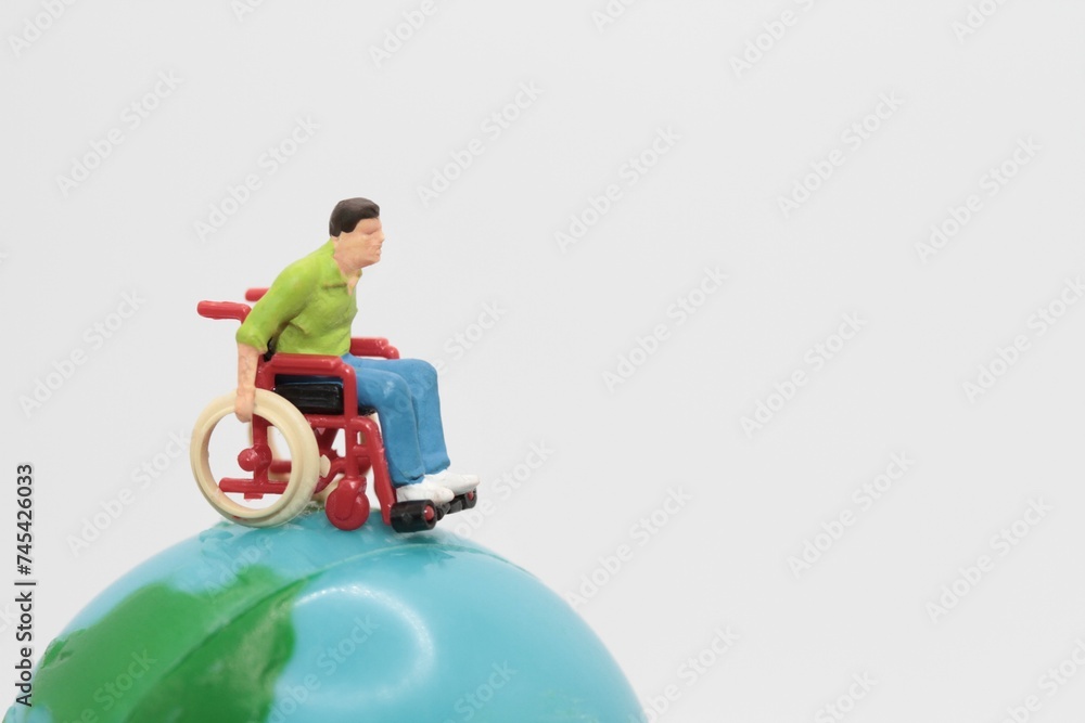 miniature figurine of a disabled man on a wheelchair on the top of a world globe miniature figurine of a disabled man on a wheelchair on the top of a world globe