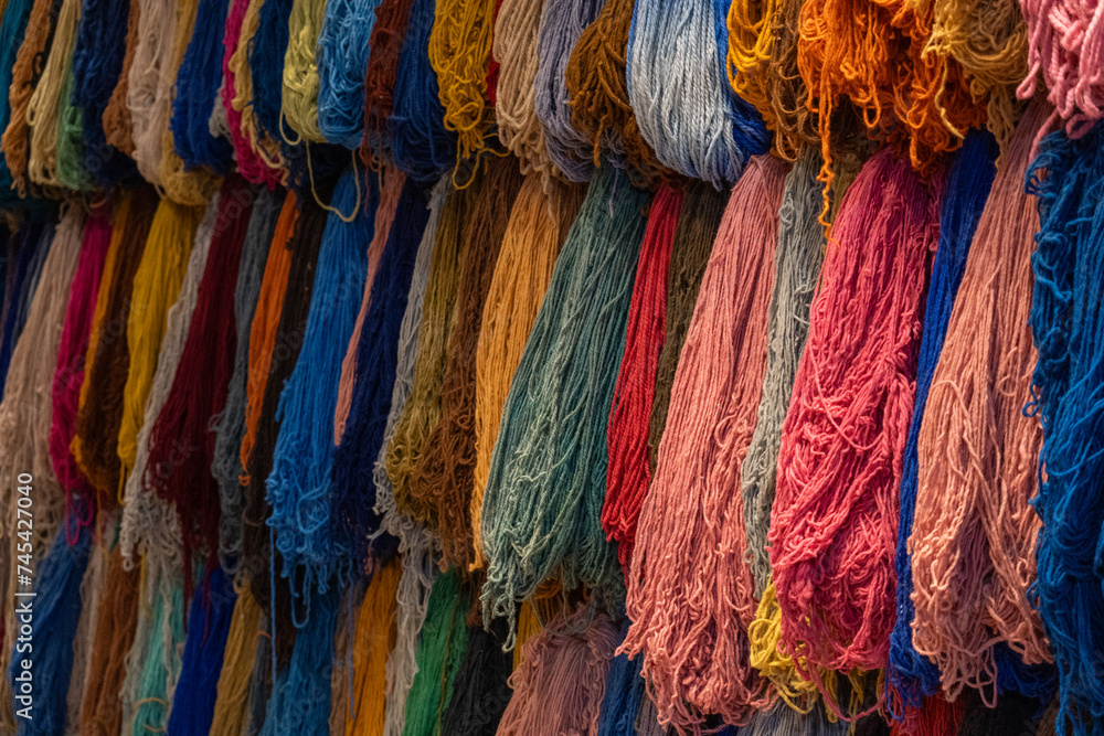 Fototapeta premium Colorful hanging fiber threads yarn for weaving handcrafted rugs, scarfs, and blankets in souk media Marrakesh, Morocco 