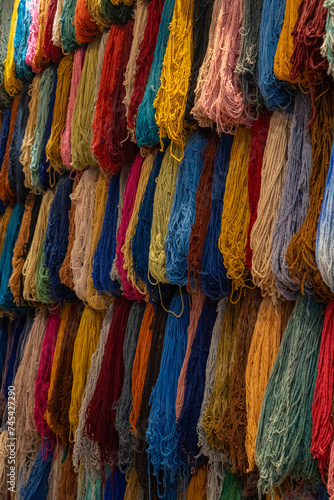 Colorful hanging fiber threads yarn for weaving handcrafted rugs, scarfs, and blankets in souk media Marrakesh, Morocco 