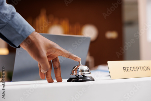 Fotografie Man standing at empty reception desk, using service call bell to get attention of hotel employees, close up