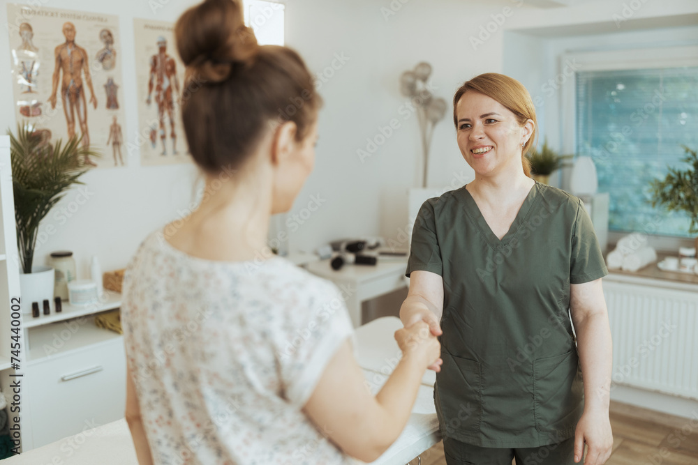 Fototapeta premium happy female therapist in massage cabinet shaking hands