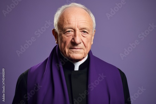 Portrait of a senior catholic priest isolated on purple background.