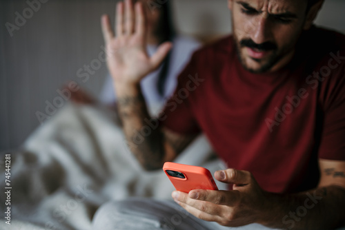 Fotografi A couple in the bedroom having a heated discussion about phone usage