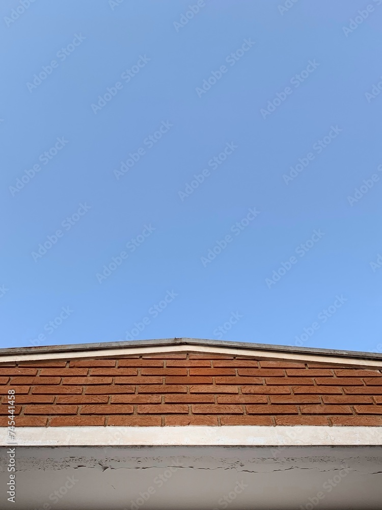 minimalist photo of house roof with a wall and blue sky minimalist photo of house roof with a wall and blue sky