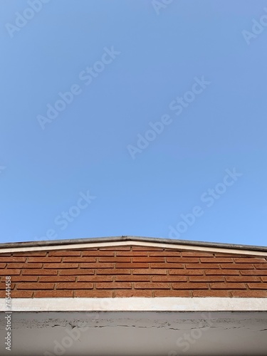 minimalist photo of house roof with a wall and blue sky