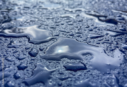 Den Haag, Netherlands - July 25 2021: water drops are laying on the roof of a freshly painted blue car