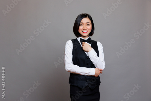 Smiling professional asian waitress wearing uniform posing for studio portrait. Confident woman restaurant receptionist standing with positive face expression and looking at camera