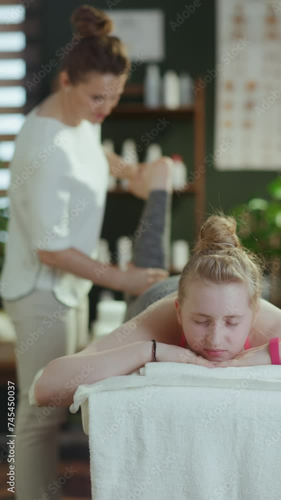 Healthcare time. massage therapist woman in massage cabinet with teenage client making massage on massage table. Healthcare time. massage therapist woman in massage cabinet with teenage client making massage on massage table.