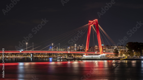 Die Willemsbrug ist eine rote  Schrägseilbrücke über die Nieuwe Maas in Rotterdam bei Nacht.