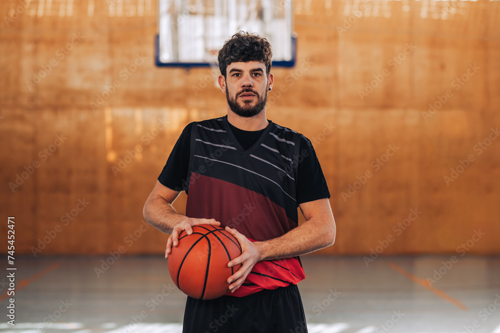 An experienced basketball player standing on court with a ball in his hands. An experienced basketball player standing on court with a ball in his hands.