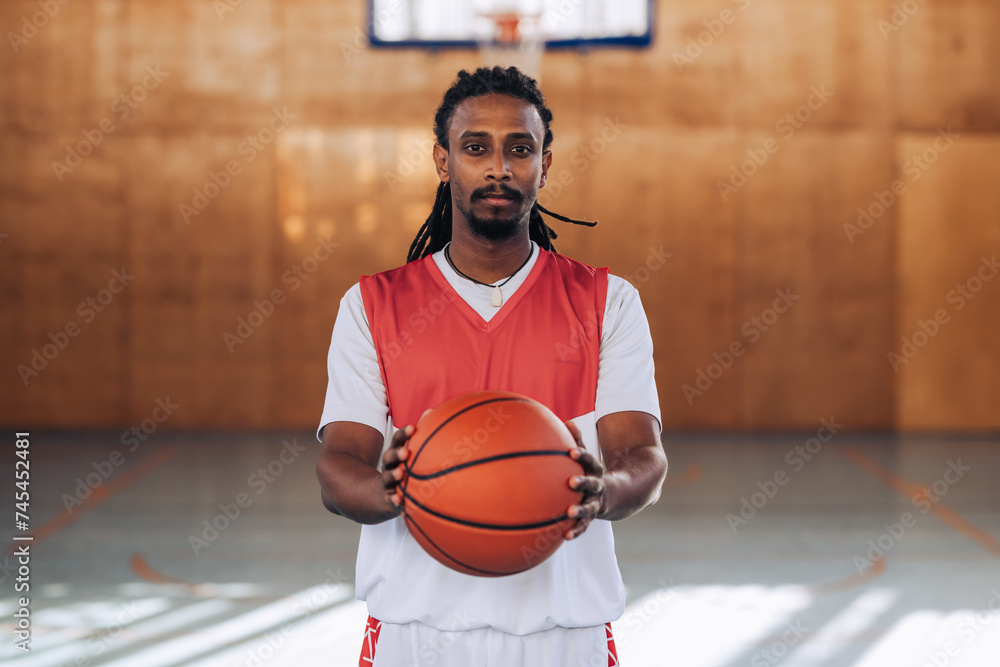 A middle-eastern basketball player on court showing a ball at the camera. A middle-eastern basketball player on court showing a ball at the camera.