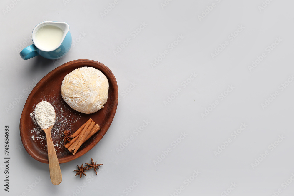 Fototapeta premium Plate with raw dough, flour, spices and milk for preparing bakery on light background