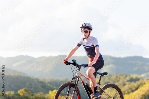 Fototapeta Naklejka Na Ścianę i Meble -  Brazilian cyclist riding his bike in the mountains. He's wearing Cycling Clothing and exercising on an outdoor trail	
