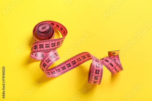 Pink measuring tape on yellow background