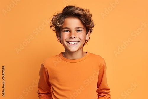 Portrait of a smiling little boy in orange sweater on orange background