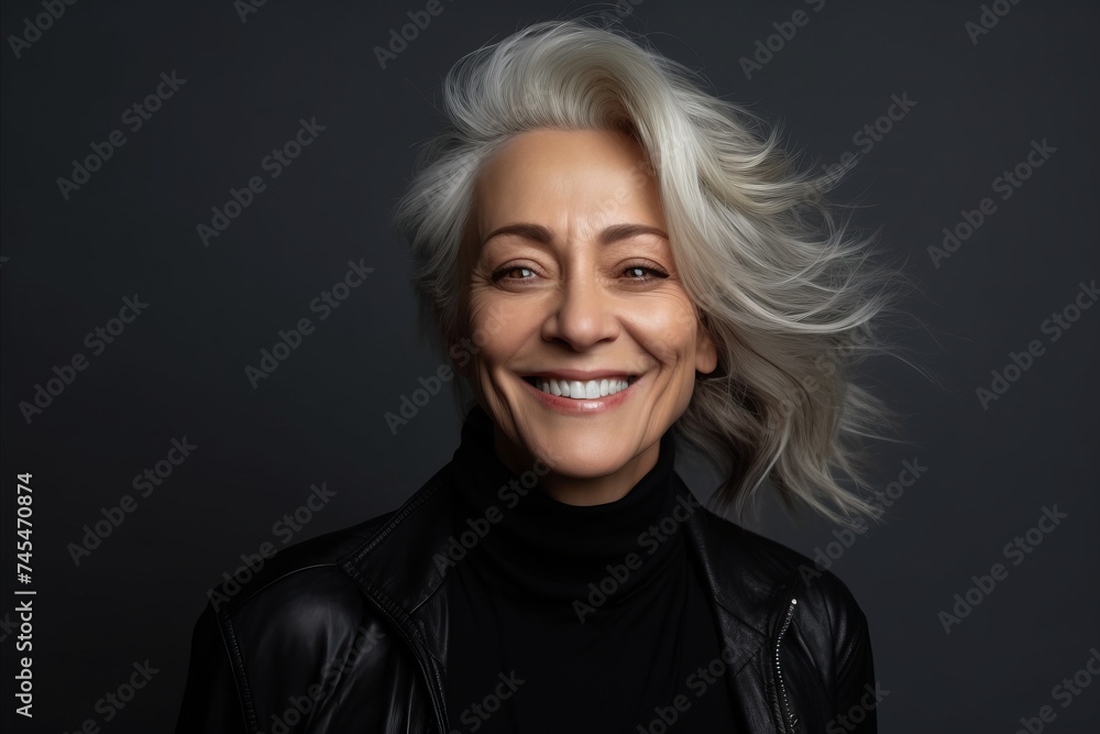 Portrait of a happy mature woman in black leather jacket on a dark background