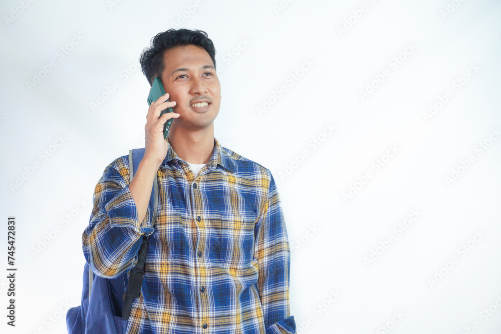 Cheerful young Asian student man wearing casual clothes with backpacks holding school books and Talking on mobile phone isolated on white background. Education in high school university college concep Cheerful young Asian student man wearing casual clothes with backpacks holding school books and Talking on mobile phone isolated on white background. Education in high school university college concep