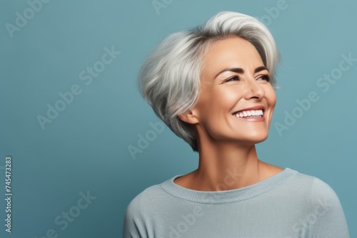 Portrait of a smiling middle-aged woman with short gray hair on a blue background