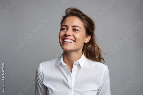 Portrait of a happy young businesswoman looking at camera over gray background