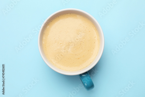 Fresh coffee in cup on light blue background, top view