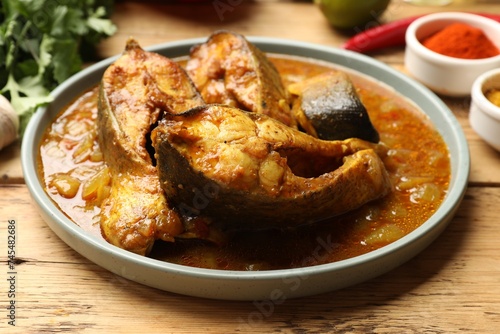 Tasty fish curry on wooden table, closeup. Indian cuisine