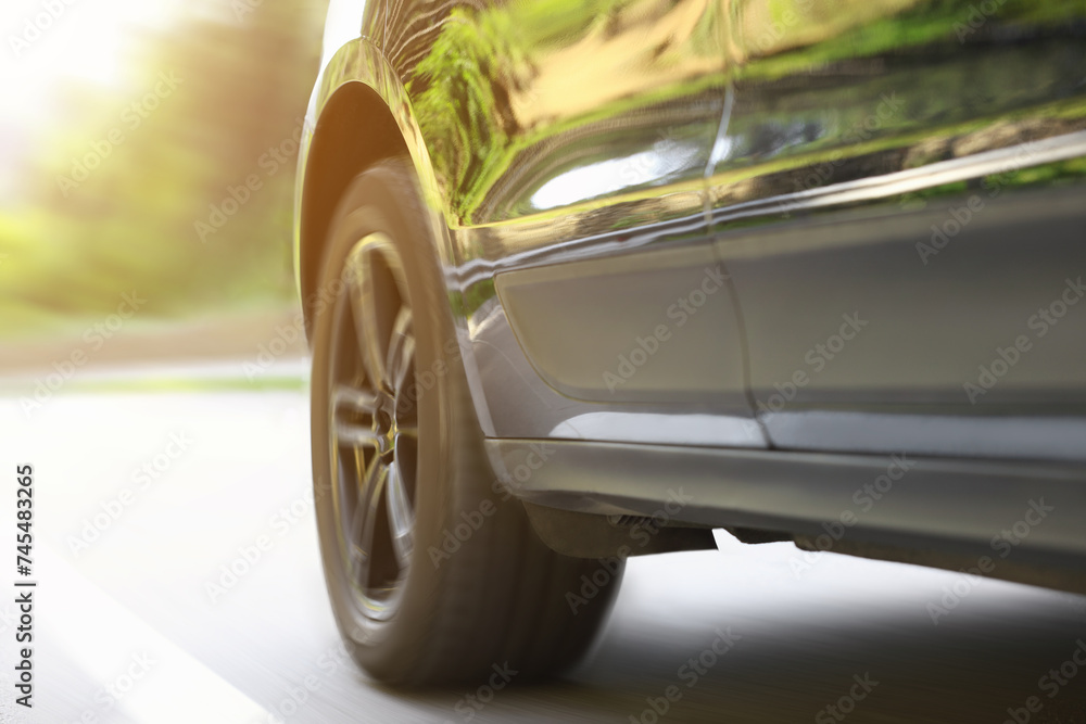 Black car driving on road outdoors, closeup with motion blur effect. Space for text