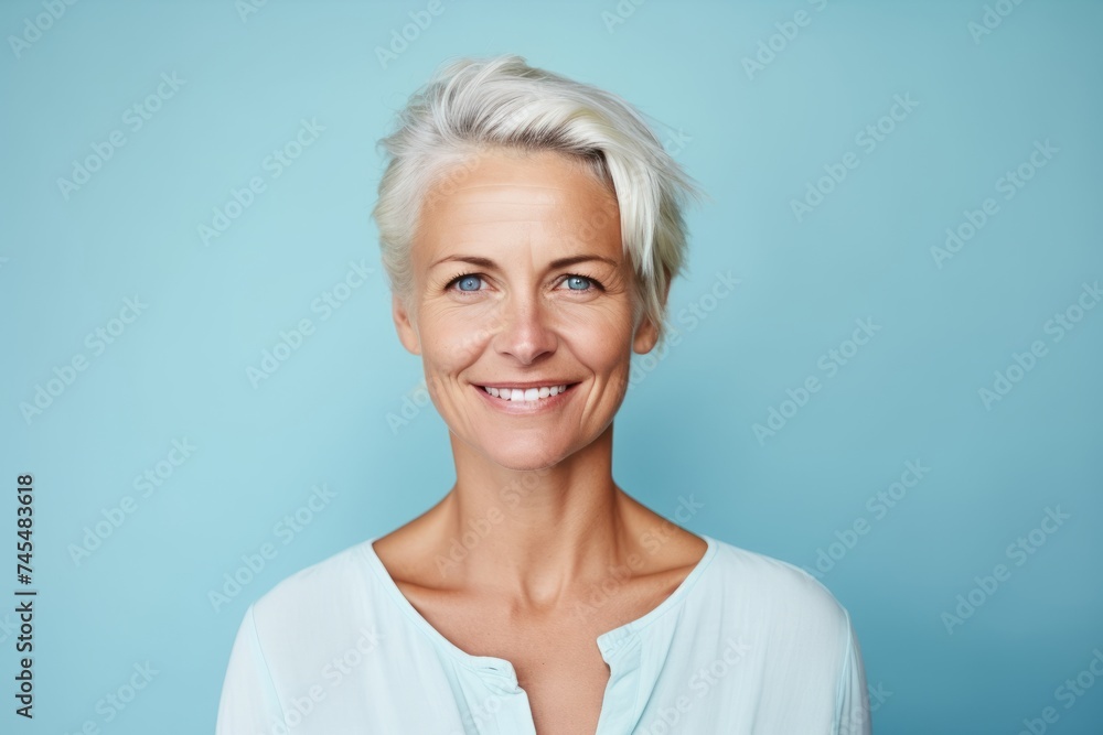Portrait of a beautiful mature woman smiling at camera against blue background Portrait of a beautiful mature woman smiling at camera against blue background