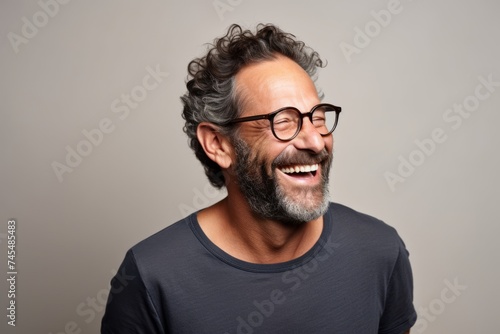 Portrait of a happy mature man with glasses laughing against gray background