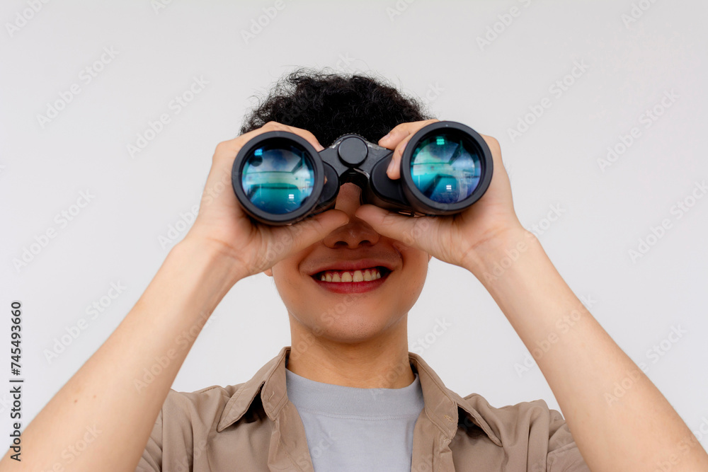 Close-up of a joyful teenager with curly hair using binoculars against a white background, feeling of discovery. Close-up of a joyful teenager with curly hair using binoculars against a white background, feeling of discovery.