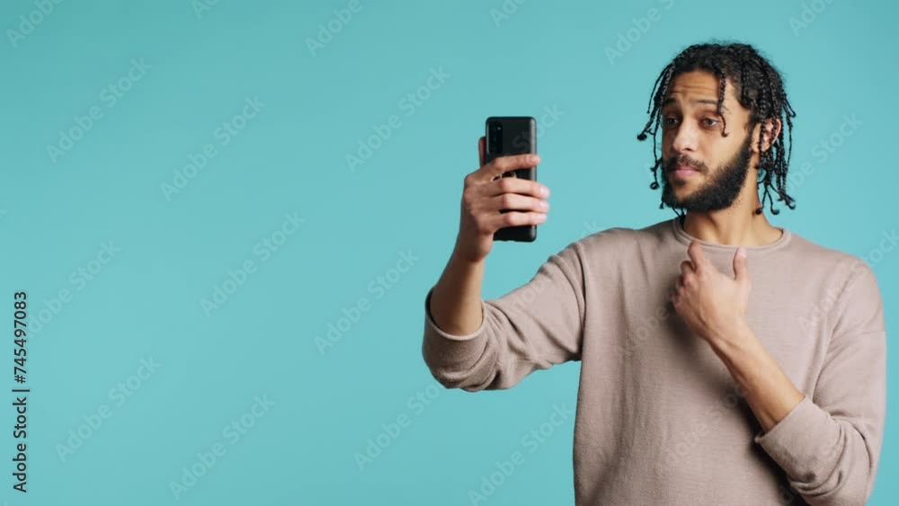 Joyous man greeting friend over online videocall on cellphone, doing friendly gestures. Excited person bonding with mate using mobile phone videoconference, studio background, camera A Joyous man greeting friend over online videocall on cellphone, doing friendly gestures. Excited person bonding with mate using mobile phone videoconference, studio background, camera A