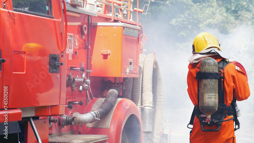 Fireman prepare equipment fighting extinguisher at fire engine truck. Firefighter fighting with smoke flame using fire hose, tube, chemical water foam spray at truck. Fireman wear hard hat protection