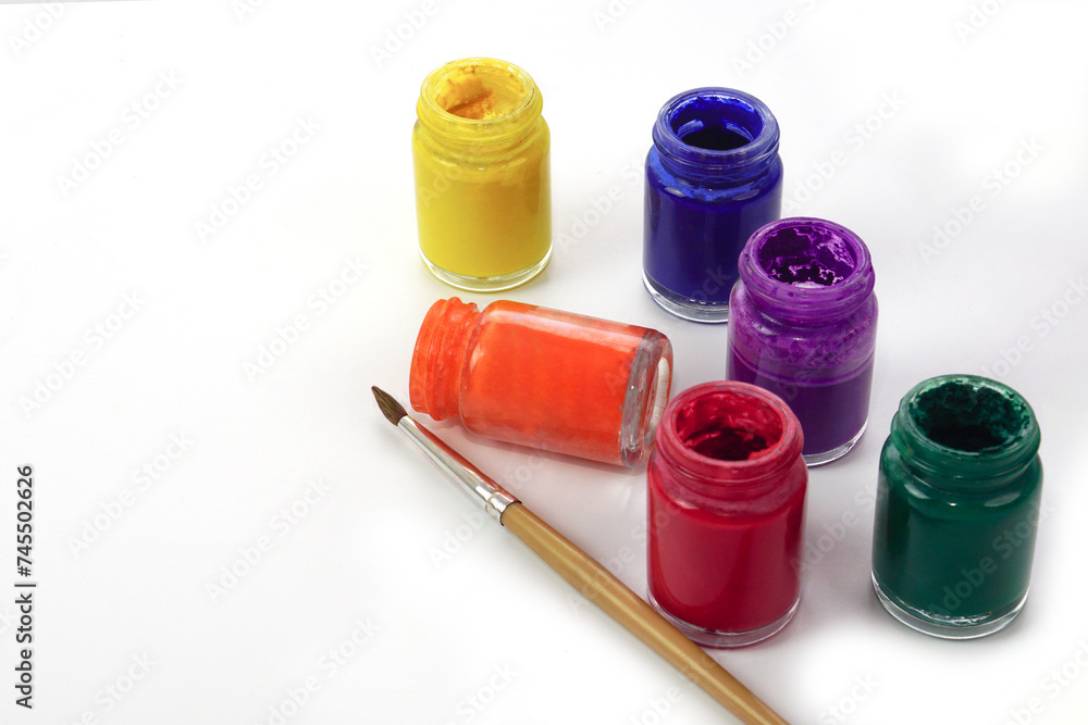 Paintbrush and watercolor bottles lined up on a white background. Learning and paintings art concept. Paintbrush and watercolor bottles lined up on a white background. Learning and paintings art concept.