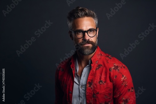 Portrait of a handsome bearded man in a red shirt and glasses.