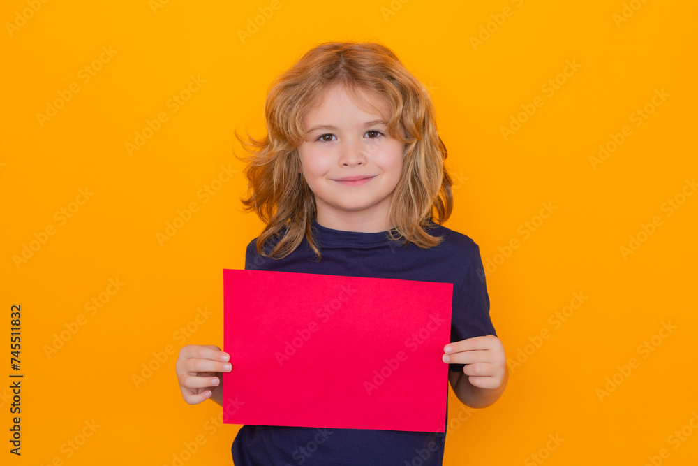 Kid hold empty sheet of paper, isolated on yellow background. Portrait of cute smiling child, isolated studio background. Happy kid, happy and smiling emotions. Kid hold empty sheet of paper, isolated on yellow background. Portrait of cute smiling child, isolated studio background. Happy kid, happy and smiling emotions.