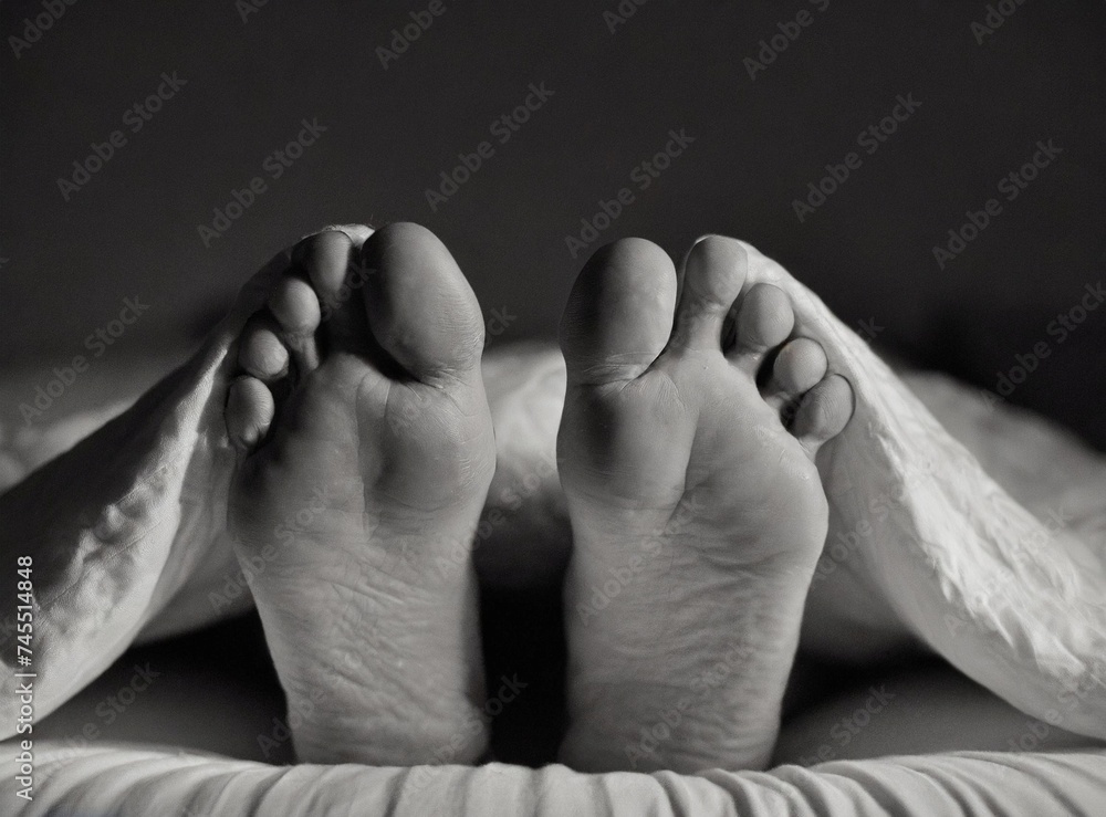 Fototapeta premium Feet of man in bed