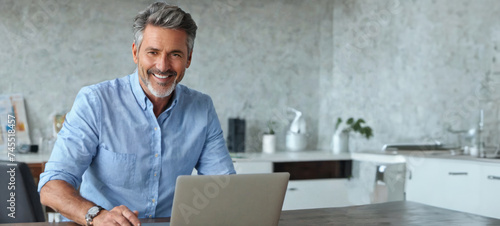 Smart grey-haired businessman working with laptop 