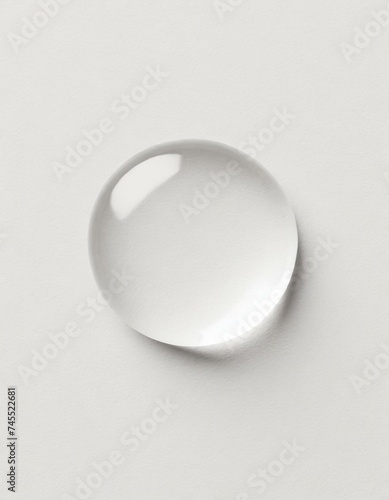 One transparent water drop. White paper background - top view 