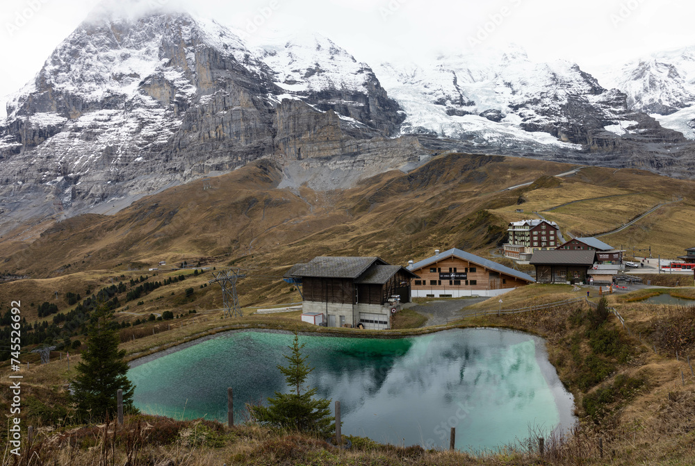 A house, reflected on a small body of water, overlooking the beautiful Eiger, autumn season